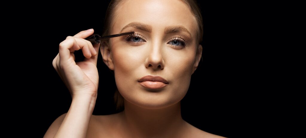 closeup portrait of young woman applying mascara with makeup brush beautiful model aga SBI 301327361